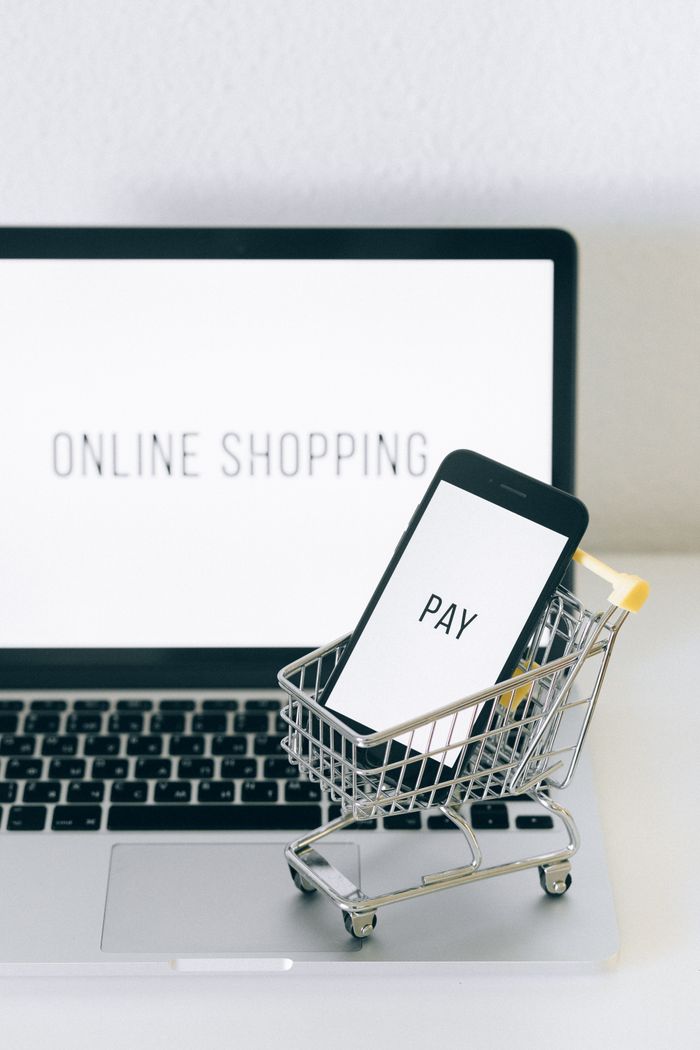 The Art of Drawing Readers In: Your attractive post title goes here A smartphone in a miniature cart on a laptop symbolizes online shopping and digital payment.